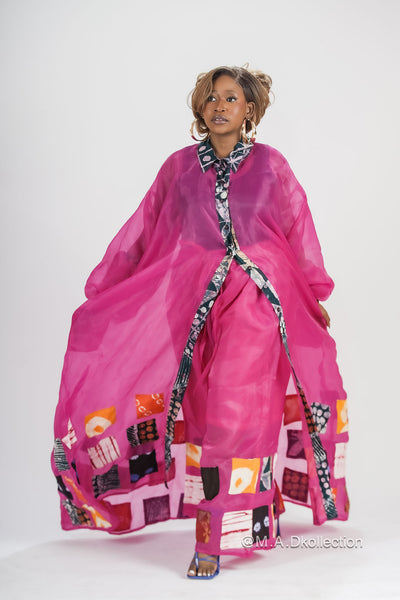 A woman modeling a pink shirt dress with adire patches and a belt. african fashion inspired fashion